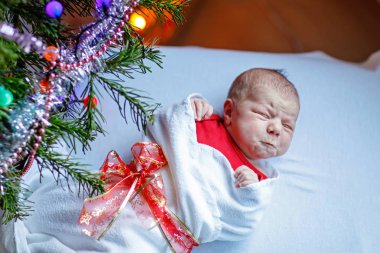Noel ağacı yakınındaki battaniyeye sarılmış bir hafta eski yeni doğan bebek