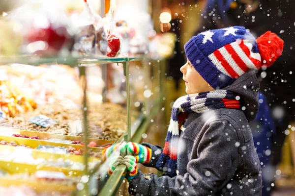 ジンジャーブレッドとお菓子と子供男の子がクリスマス マーケットの上に立つ — ストック写真