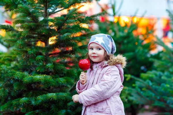 Niña comiendo manzana cristalizada en el mercado de Navidad — Foto de Stock