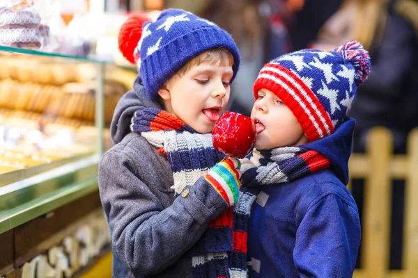 Dois garotinhos comendo doces de maçã no mercado de Natal — Fotografia de Stock