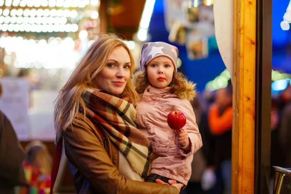 Donna e bambina che mangiano mela cristallizzata al segno di Natale — Foto Stock