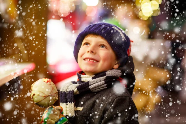 Petit garçon mangeant du sucre pomme bonbons stand sur le marché de Noël — Photo