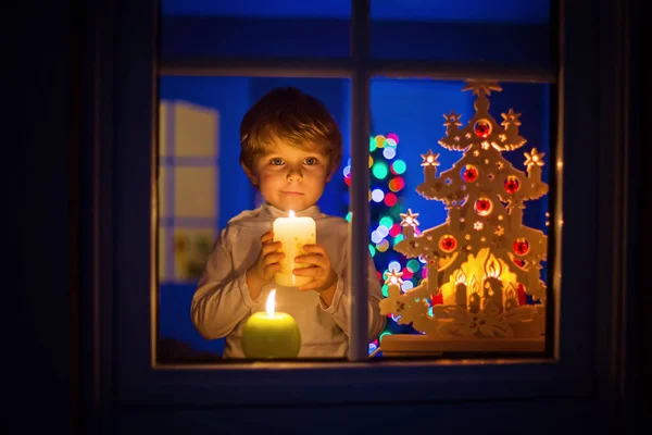 Ragazzino in piedi vicino alla finestra a Natale e tenendo — Foto Stock