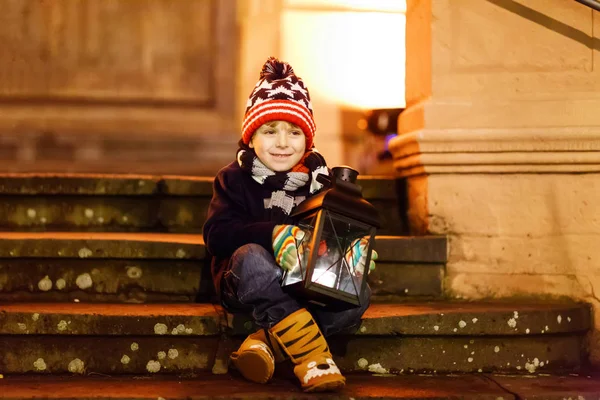 Little cute kid boy with with a light lantern on stairs near church. — Stock Photo, Image