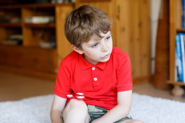 Niño de la escuela jugando con Tri Fidget Hand Spinner en interiores — Foto de Stock