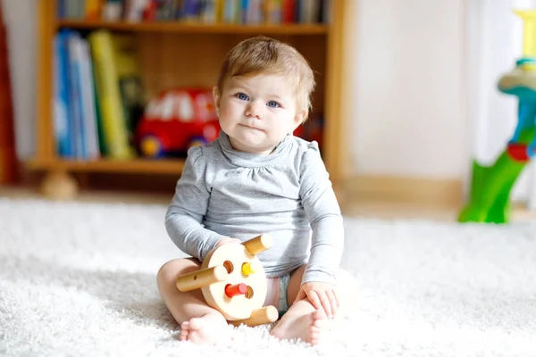 Bayi perempuan yang manis bermain dengan mainan kayu pendidikan di kamar bayi — Stok Foto