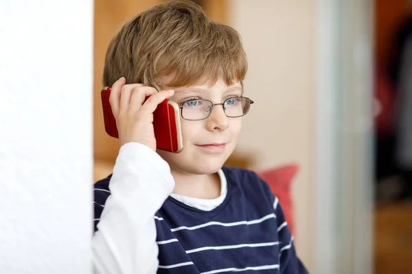 Милый маленький мальчик в очках говорит по сотовому телефону — стоковое фото
