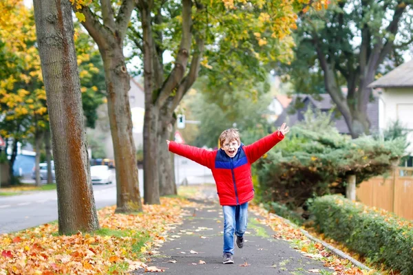 Happy little boy running on autumnal street after school. — Stock Photo, Image