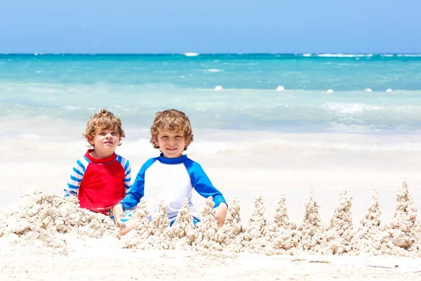 Playa del Carmen, Meksika 'da tropik plajlarda kumdan kale inşa eden iki çocuk. — Stok fotoğraf