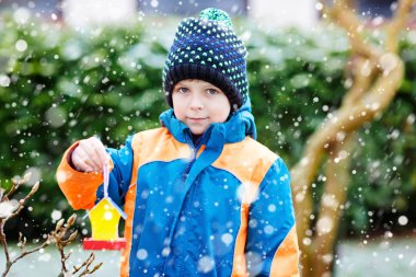 Küçük çocuk çocuk kuş evi kış aylarında beslenme için ağaç üzerinde asılı
