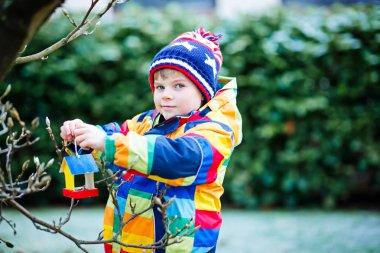 Küçük çocuk çocuk kuş evi kış aylarında beslenme için ağaç üzerinde asılı