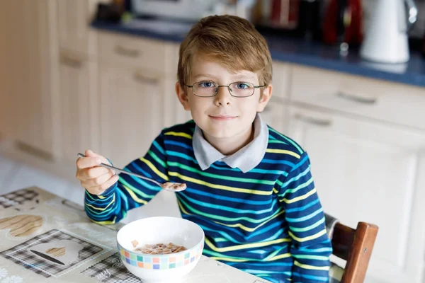 Menino loiro feliz comendo cereais no café da manhã ou almoço. Alimentação saudável para crianças . — Fotografia de Stock