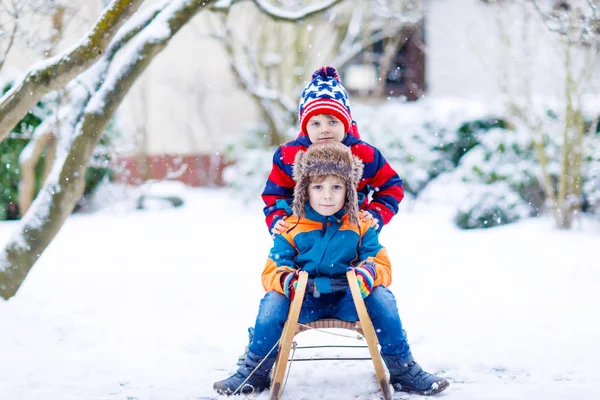 Два маленьких мальчика наслаждаются катанием на санях зимой — стоковое фото