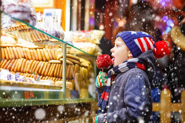 クリスマス マーケットに立つ小さな子供男の子食べる砂糖リンゴ菓子 — ストック写真