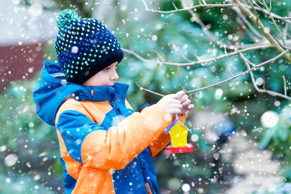 Liten unge pojke hängande fågel hus på träd för utfodring vintertid — Stockfoto