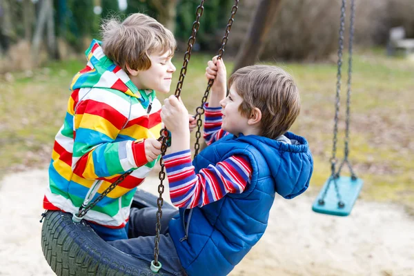 Két kis gyerek fiú birtoklás móka-val lánc hinta a szabadtéri játszótér — Stock Fotó