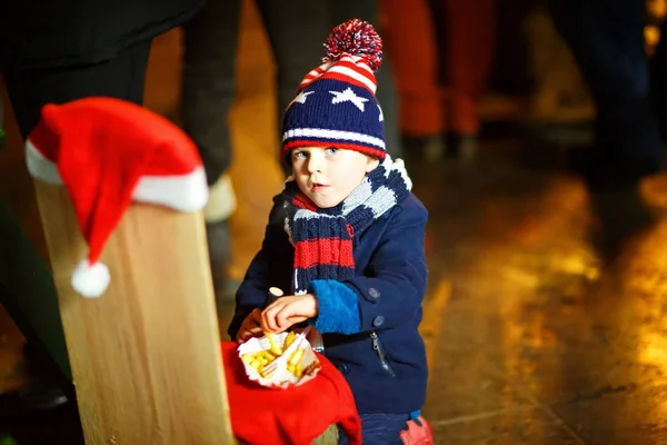 Petit garçon mignon mangeant des frites sur le marché de Noël — Photo