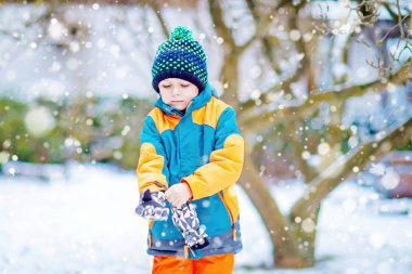 Mutlu çocuk kışın karla eğleniyor.