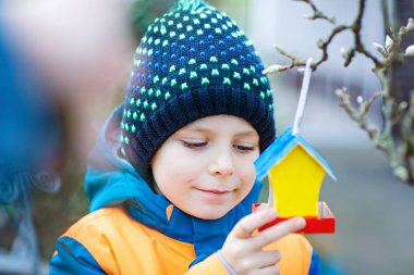 Küçük çocuk kuş evi kış aylarında beslenme için ağaç üzerinde asılı