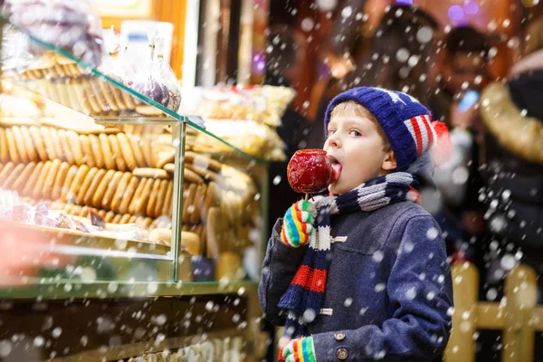 Menino comendo açúcar doce de maçã stand no mercado de Natal — Fotografia de Stock