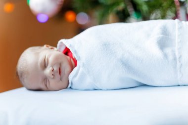 Noel ağacı yakınındaki battaniyeye sarılmış bir hafta eski yeni doğan bebek