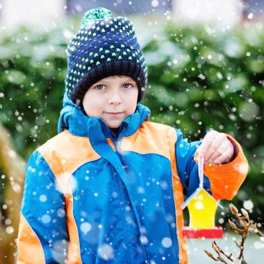 Küçük çocuk çocuk kuş evi kış aylarında beslenme için ağaç üzerinde asılı