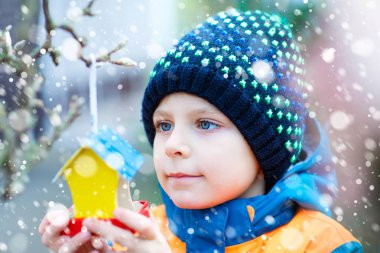 Küçük çocuk kuş evi kış aylarında beslenme için ağaç üzerinde asılı