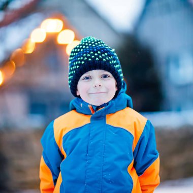 Mutlu çocuk kışın karla eğleniyor.