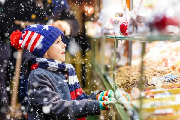 ジンジャーブレッドとお菓子と子供男の子がクリスマス マーケットの上に立つ — ストック写真