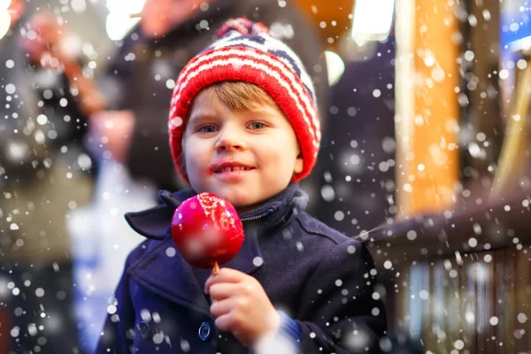 Menino pequeno comendo maçã doce no mercado de Natal — Fotografia de Stock