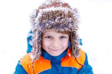 Mutlu çocuk kışın karla eğleniyor.