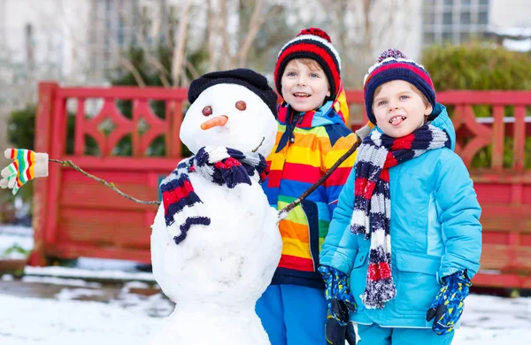 Twee broers en zussen jongetjes een sneeuwpop maken — Stockfoto