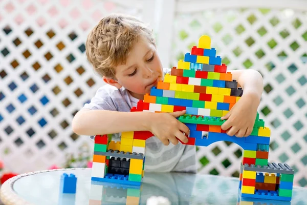 Pequena criança loira e garoto brincando com muitos blocos de plástico coloridos. — Fotografia de Stock