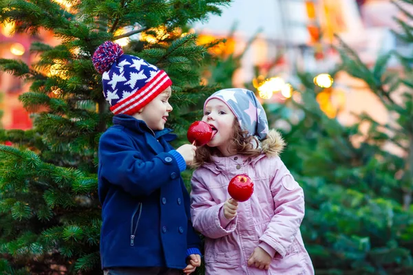Dvě malý děti jíst vykrystalizoval apple na vánoční trh — Stock fotografie