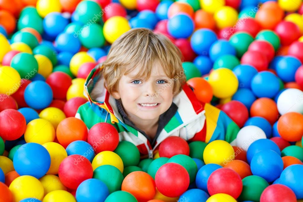 Un niño lindo está jugando en una piscina de bolas de plástico