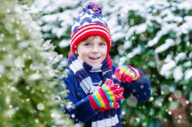 Mutlu çocuk kışın karla eğleniyor.