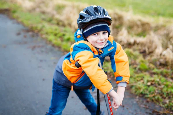 Schattige preschool jongen jongen rijden op scooter in park — Stockfoto