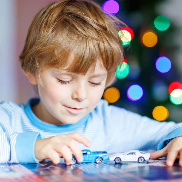 Little blond child playing with cars and toys at home — Stock Photo, Image