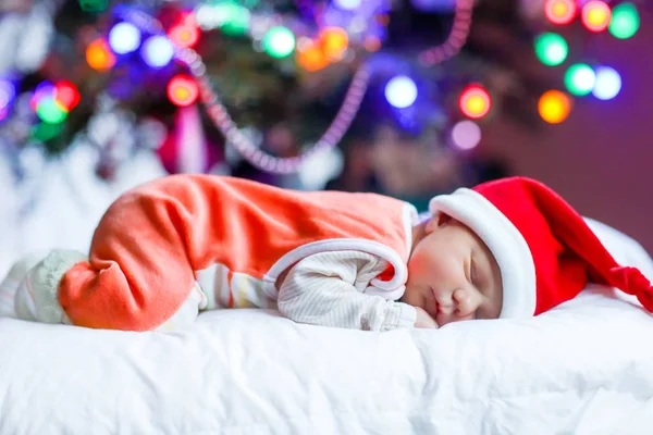 Un bébé d'une semaine dans le chapeau de Père Noël près de l'arbre de Noël — Photo