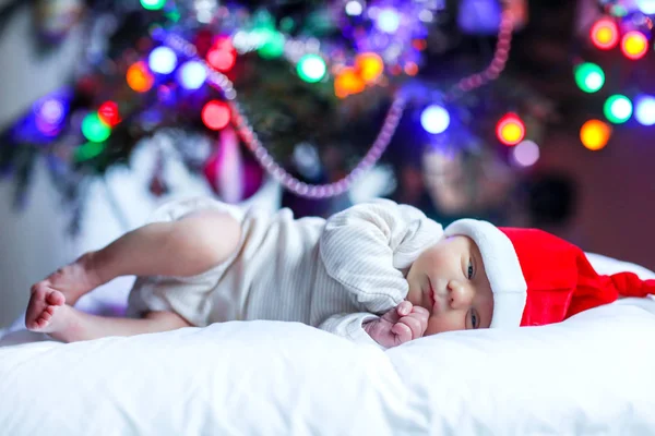 Un bébé d'une semaine dans le chapeau de Père Noël près de l'arbre de Noël — Photo