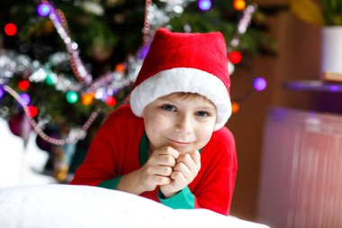 Noel ağacı ve arka plan ışığı ile Noel Baba şapkalı küçük çocuk çocuk.