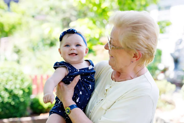 Cute little baby girl with grandmother on summer day in garden — Stock Photo, Image