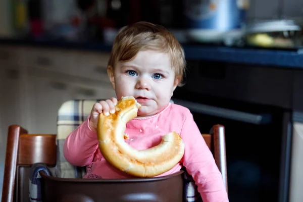 Cute little baby girl eating bread. Child eating for the first time piece of pretzel. — Stock Photo, Image