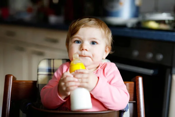 Cute adorable ewborn baby girl holding nursing bottle and drinking formula milk — Stock Photo, Image