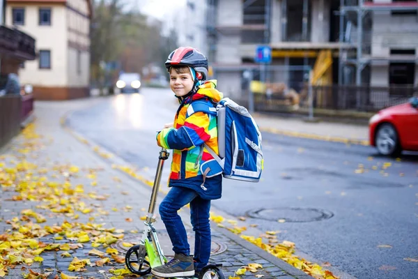 Милый маленький мальчик едет на скутере по дороге в школу — стоковое фото