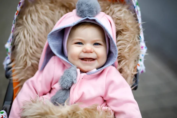 Schattig klein mooie babymeisje, zittend in de kinderwagen of wandelwagen op herfstdag — Stockfoto
