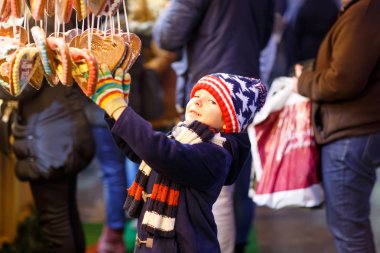 Küçük şirin çocuk çocuk satın alma tatlı bir cancy gelen Noel pazarı üzerinde durmak