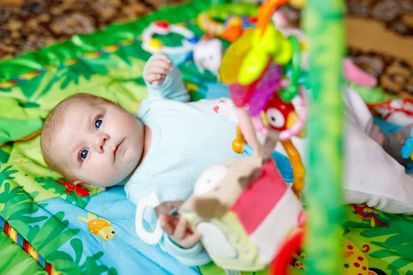 Мила чарівна новонароджена дитина грає на барвистому іграшковому тренажерному залі — стокове фото