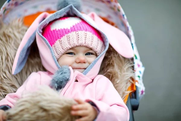 Schattig klein mooie babymeisje, zittend in de kinderwagen of wandelwagen op herfstdag — Stockfoto