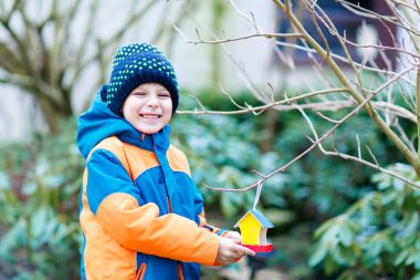 Küçük çocuk çocuk kuş evi kış aylarında beslenme için ağaç üzerinde asılı